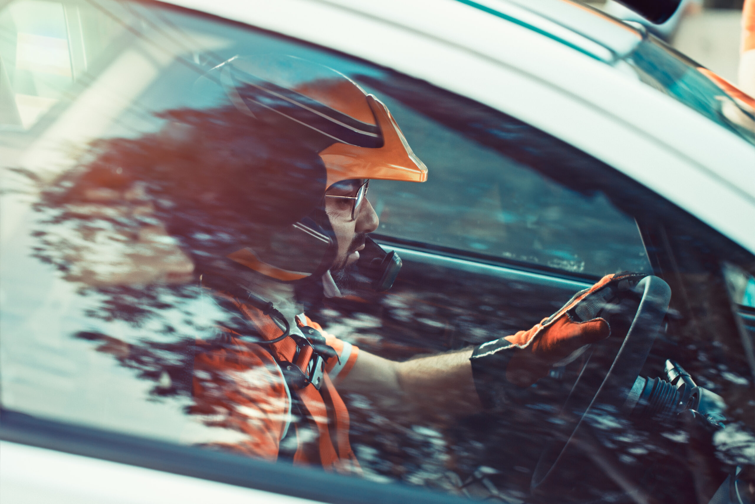 Rally driver, the man in the helmet tensely and seriously looking forward, side view through the car window at the racer participating in the rally, racing competition